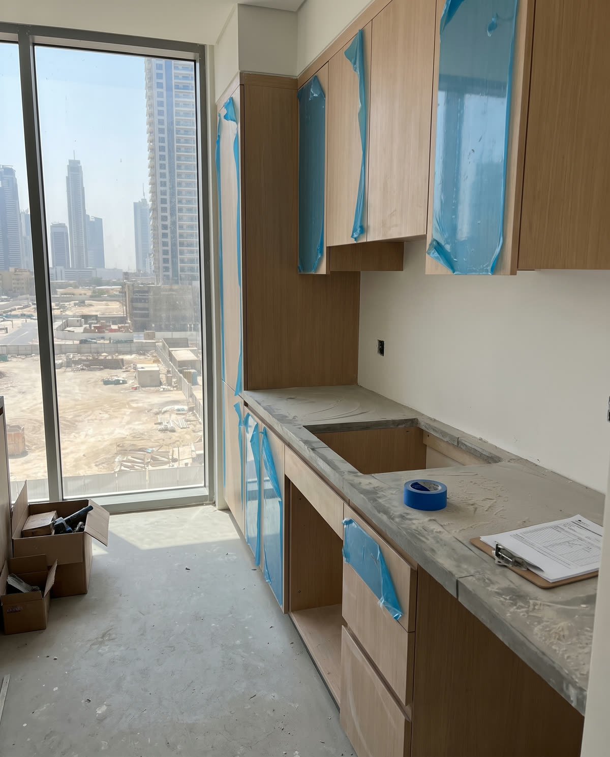 Küche im Ausbau in einem Hochhaus in Dubai, Fronten noch abgeklebt, dahinter die Stadt